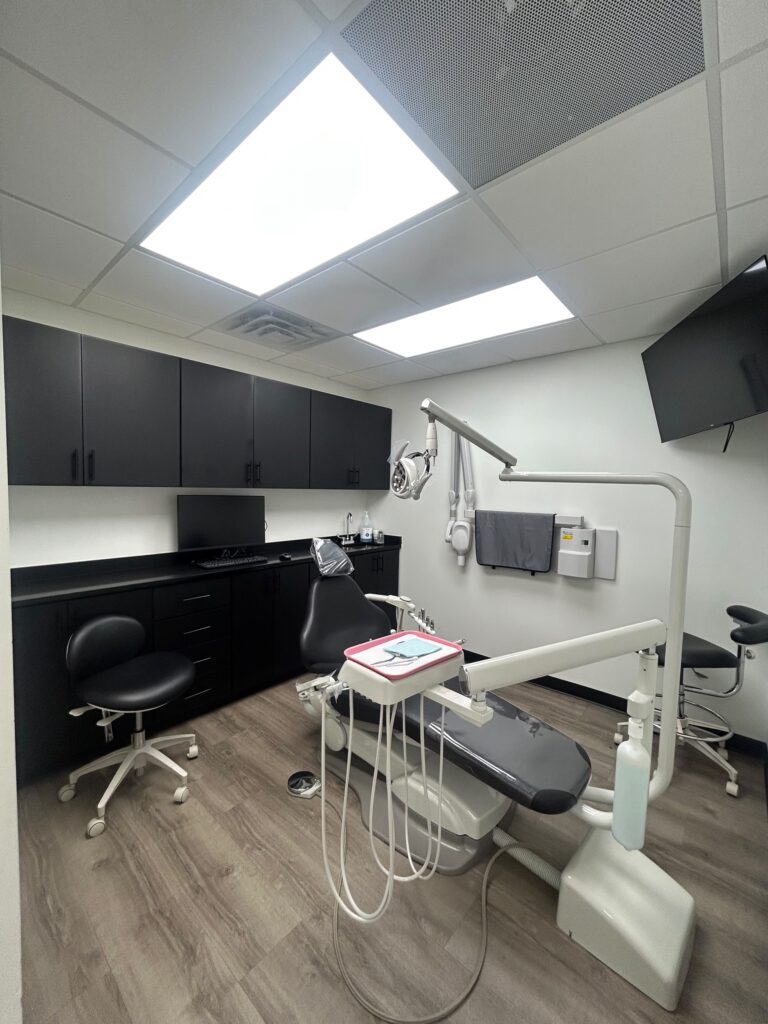 Treatment room with chair, overhead light and X-ray unit at Motor City Dental Group in Detroit